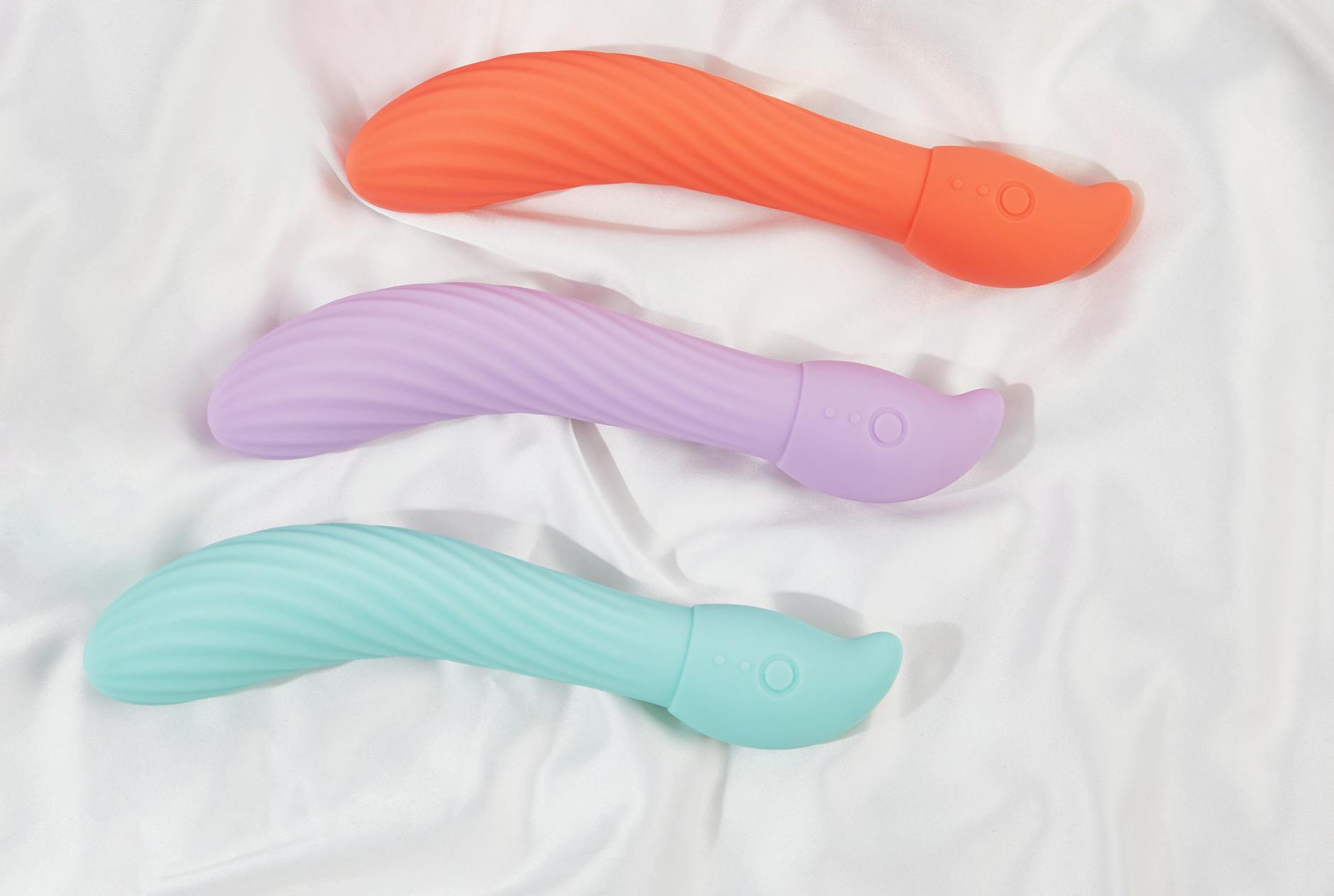 Close-up of colorful clitoral vibrators arranged on white fabric.