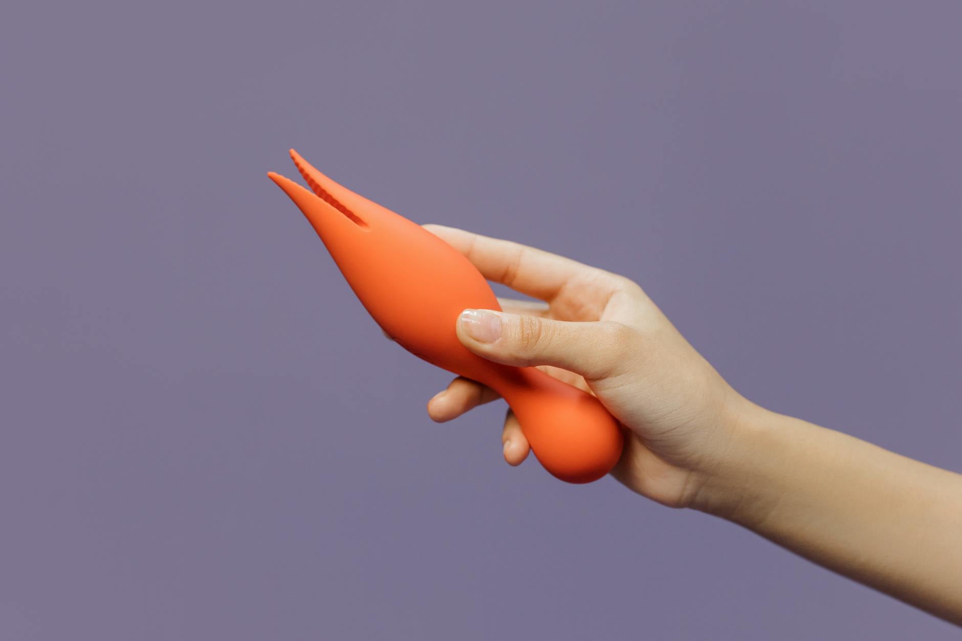 A hand holding a vibrator against a purple backdrop showcasing modern sensuality