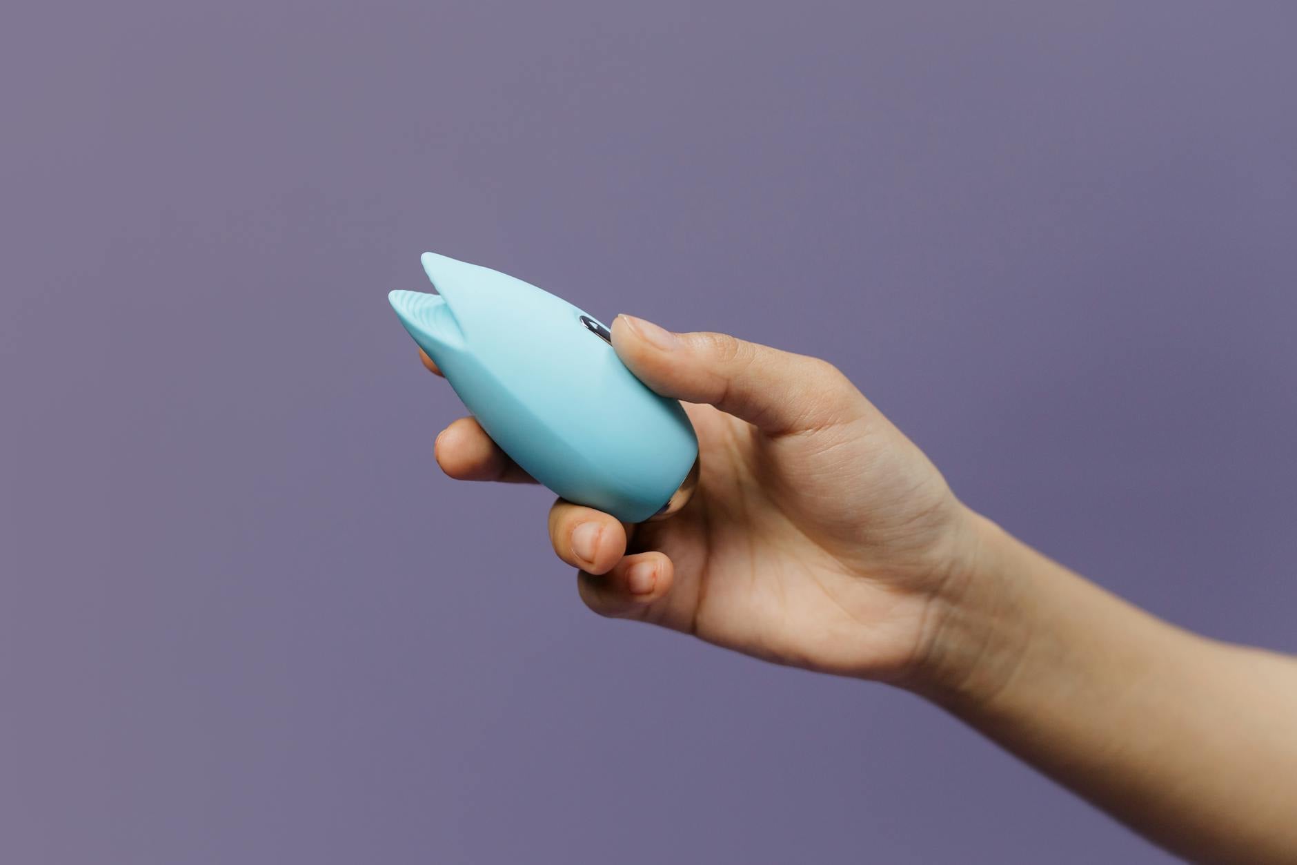A lemon vibrator held in hand against a soft purple background, symbolizing self-care and pleasure.