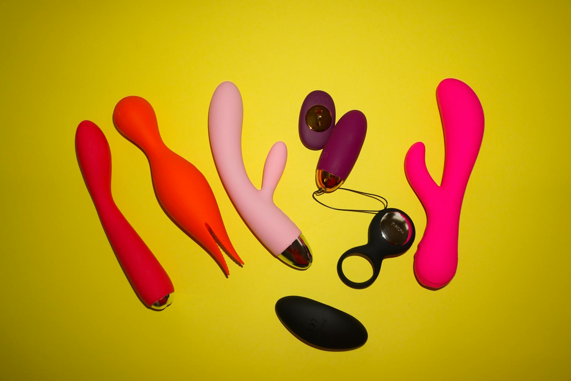 Image de trois vibrateurs colorés sur fond jaune lumineux, illustrant la variété des jouets sexuels modernes