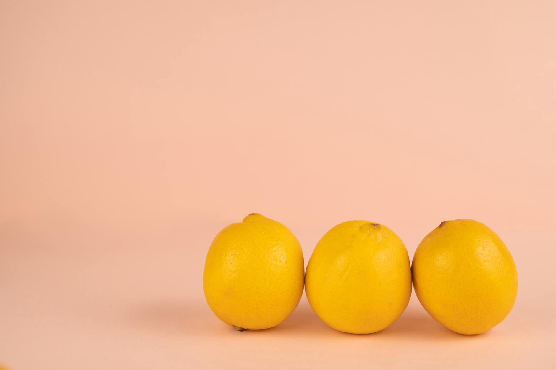 Two hands holding pink and blue lemon vibrators against a pastel background